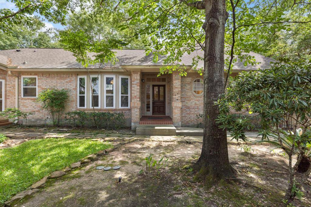 A peaceful yard shaded by mature trees creates a warm and inviting approach to the home’s main entrance.