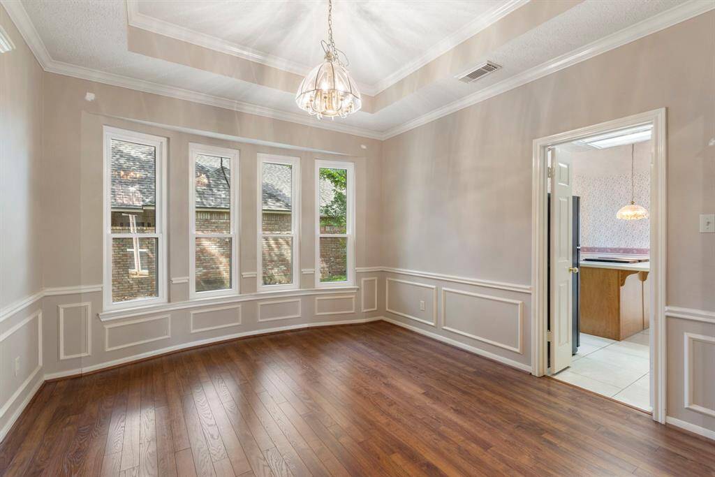The formal dining room features elegant wainscoting, a tray ceiling, and bay windows that fill the space with natural light.
