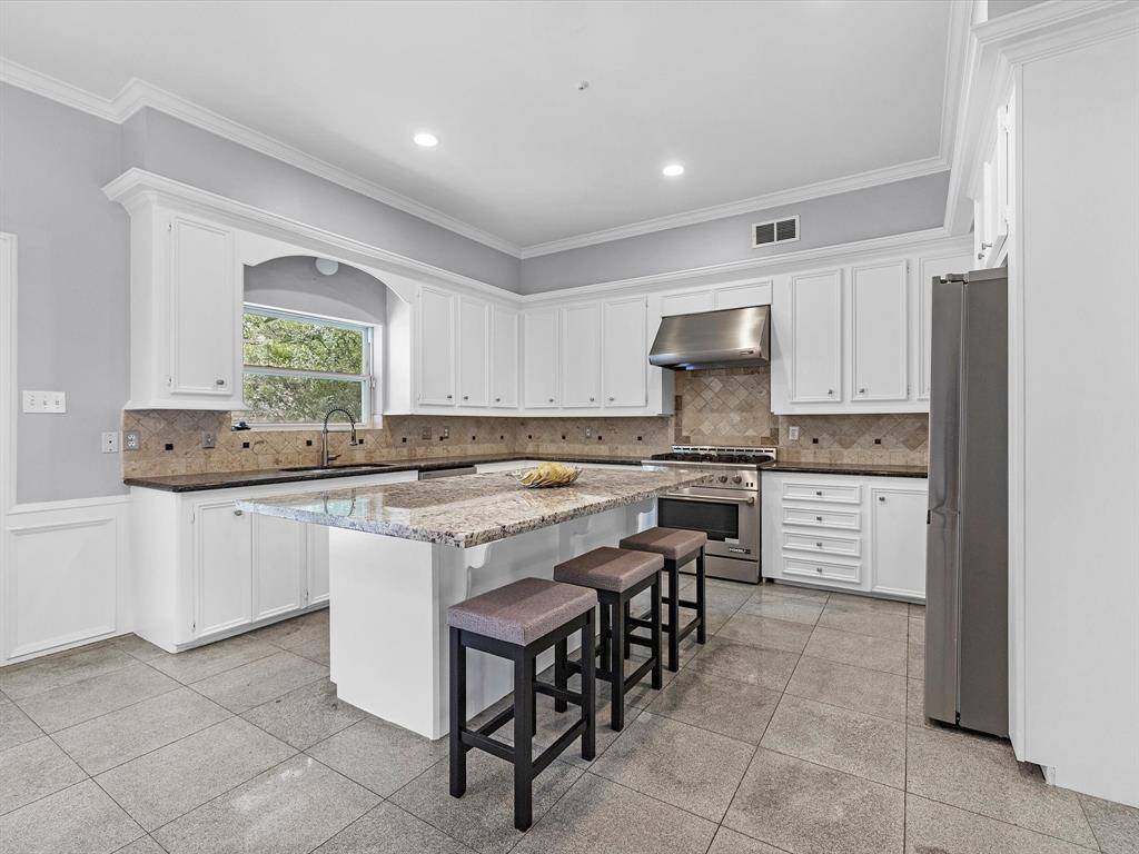 The expansive kitchen includes grantie countertops, an island and stainless steel appliances.