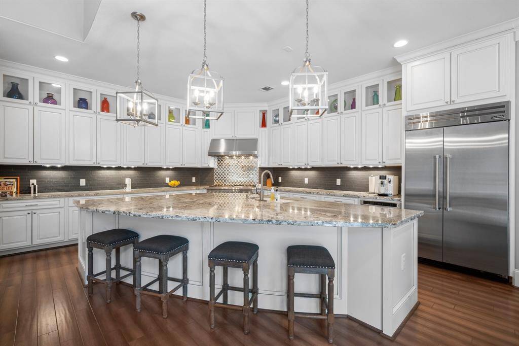 Gourmet chefs and home cooks alike will be inspired in this spacious kitchen, showcasing elegant wood-look tile flooring and a large island with curved breakfast bar seating for six. Sleek granite countertops, recessed lighting, crown molding, and high-end Thermador appliances add modern style, while thoughtful features like a pull-out trash/recycle drawer, slow-close drawers and cabinets, a pot-filler, and under-cabinet lighting enhance functionality . There's plenty of space to create, gather, and enjoy.