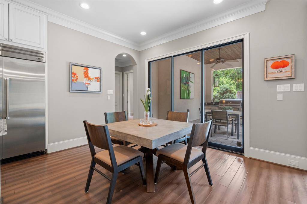 Start your mornings with a cup of coffee or gather for family dinners in this inviting breakfast area! Featuring wood-look tile flooring, triple crown molding, recessed lighting, and a wall of sliding retractable glass door panels, this space is filled with natural light. Enjoy panoramic views while dining, and this area can also be opened up for seamless entertaining to the outside covered porch.