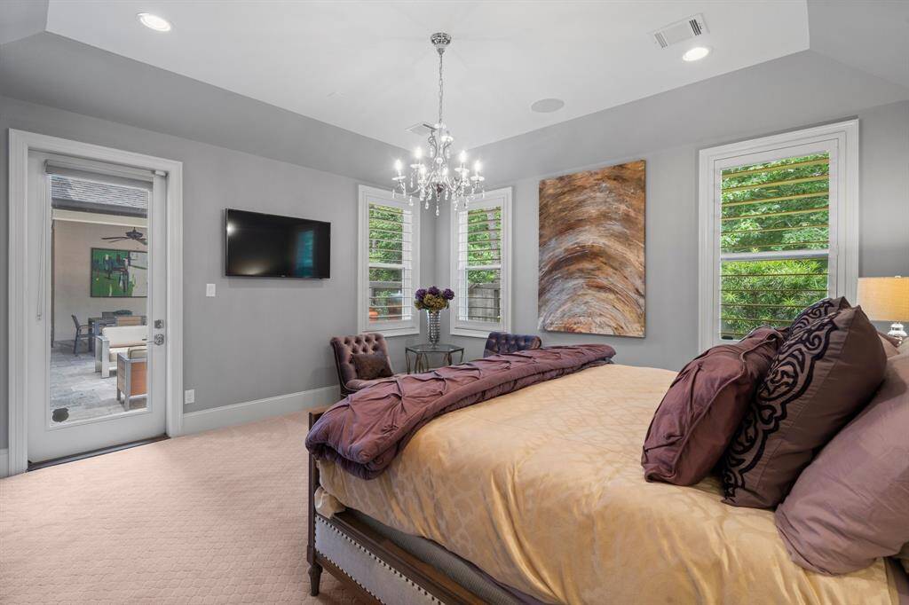 The inviting Owner’s Suite is a private retreat designed for ultimate relaxation, located in a private wing of the home. A stunning cove ceiling with recessed lighting adds architectural elegance, while lush carpeting, 9” baseboards,  and a stylish chandelier complete the refined look. There is also direct access to the patio and water/fire features. Spacious, serene, and beautifully appointed — the perfect escape at the end of the day.