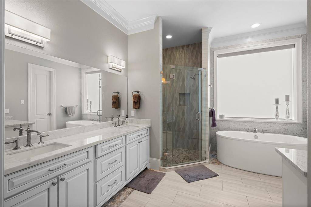 Truly a retreat for getting ready on a busy morning or stealing away for an evening out, your en-suite bath features double door entry, rectangular tile flooring, triple crown molding, recessed lighting, dual sinks with additional stand-alone vanity area, large shower, vessel soaking tub, sunny window, private commode,  and large walk-in closet with built-in shelving.