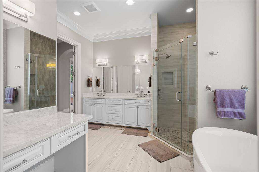 The dual vanities showcase rich cabinetry, gleaming marble counter tops, under-mount sinks, and a large mirror.  A separate lighted sit-down vanity area for her creates ample room for pampering.