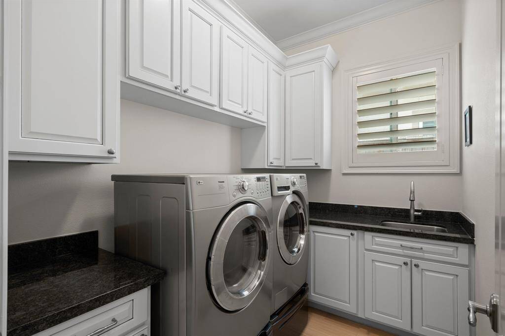 Utility room is conveniently located for easy laundry time! The laundry room features rectangular tile flooring, crown molding, upper and lower cabinets for storage, utility sink, sunny window, and a folding counter. Washer and dryer included!