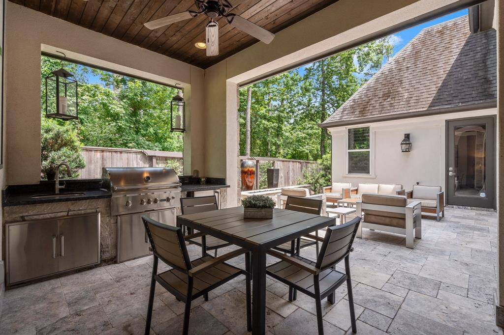 This beautifully designed covered patio is the perfect spot to unwind — whether enjoying a glass of wine, grilling dinner, or relaxing by the fire feature.  It features a beautiful wood slat ceiling, recessed lighting, travertine tile flooring, ceiling fan, and an incredible outdoor kitchen.  The nearby patio offers additional space for dining and entertaining.