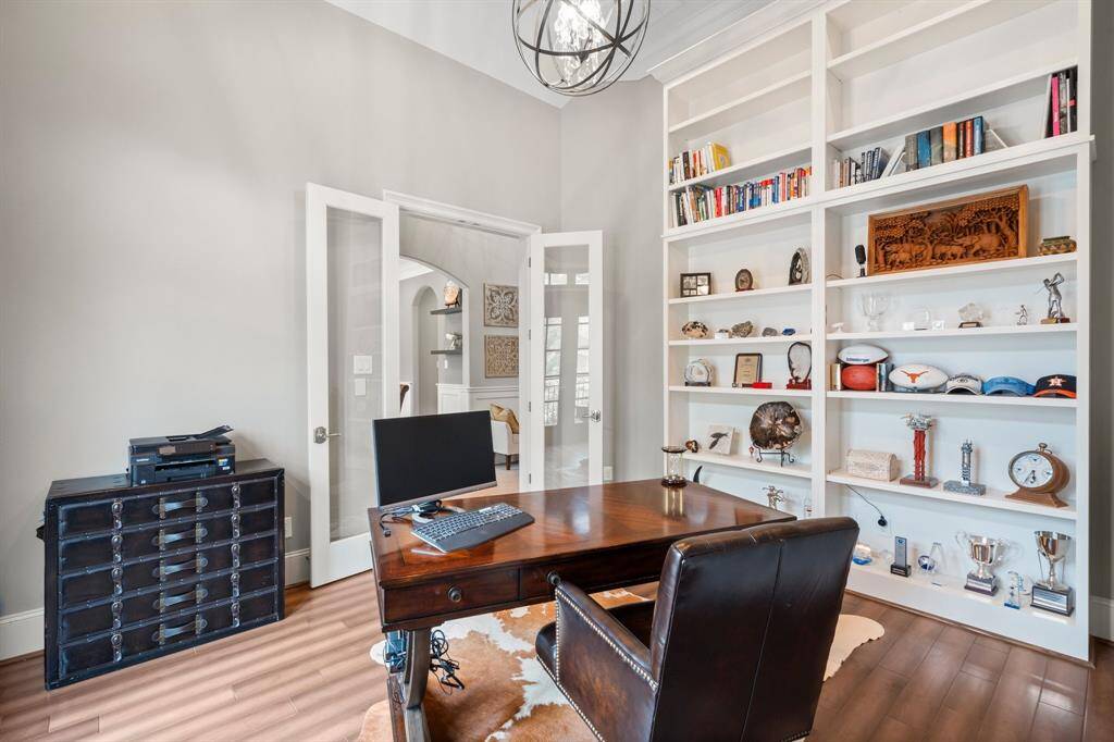 The study features floor-to-ceiling built-in shelving, offering elegant display space for books, art, and collectibles. Glass-front French doors provide both privacy and sound control while maintaining a visual connection to the rest of the home.