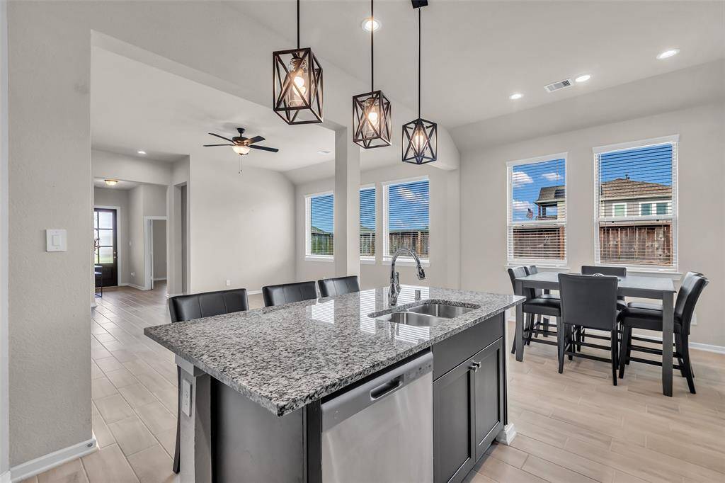 Stylish droplights hang above the kitchen island, adding character to the space. From this vantage point, the living room and dining area are clearly visible, highlighting the open layout.