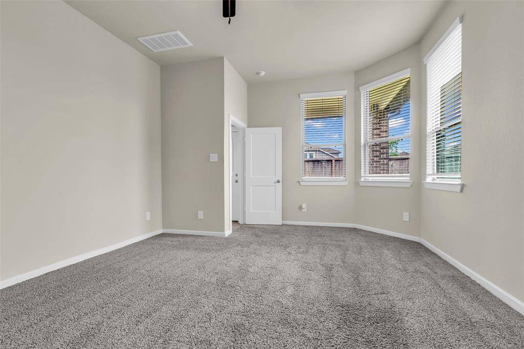 The primary bedroom, located at the back of the first floor, features carpeted floors and large windows that provide a view of the backyard.