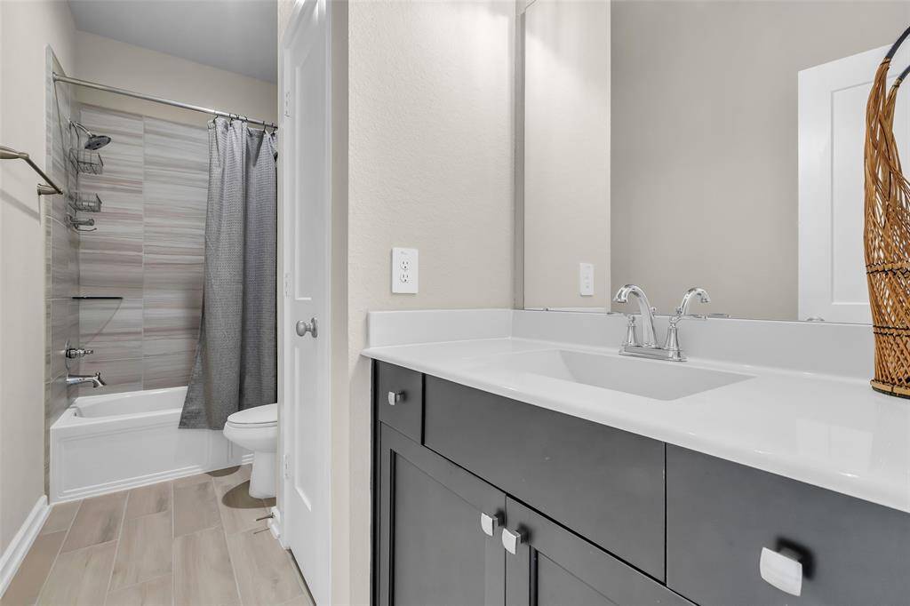 The common bathroom features a tub and shower combo, a single sink, and additional storage behind a closed door for convenience.