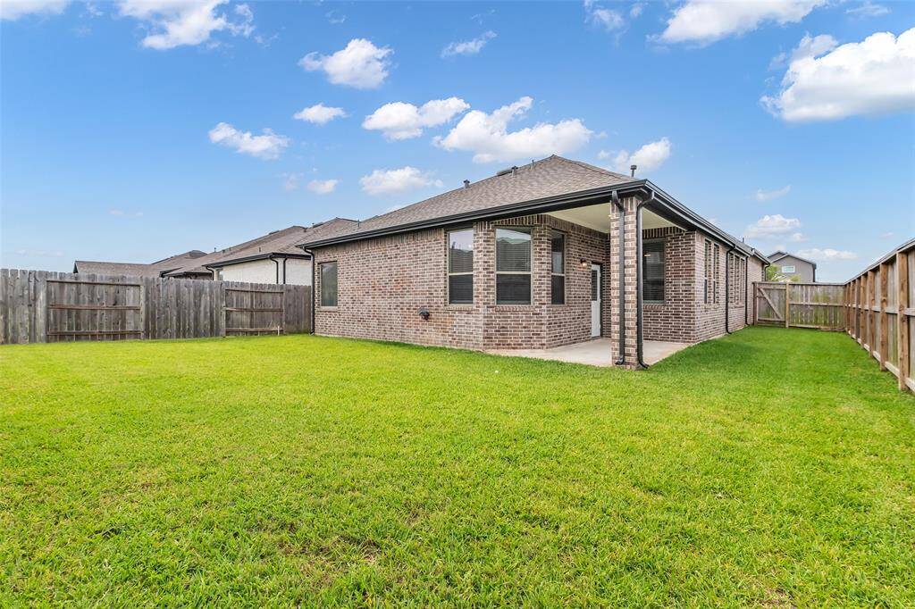 The backyard features lush green grass and is fully enclosed by a tall wooden fence, providing privacy and space for outdoor activities.