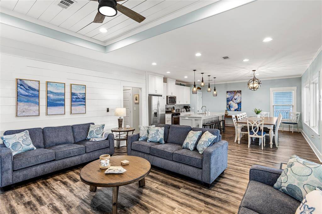 Living room is open to dining room and kitchen and features shiplap and crown molding