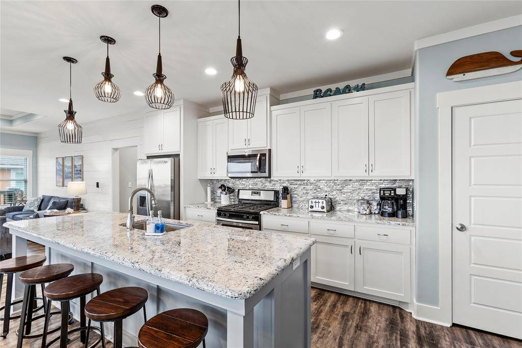 Elegant kitchen features granite countertops, stainless steel appliances, pantry, and pendant lighting