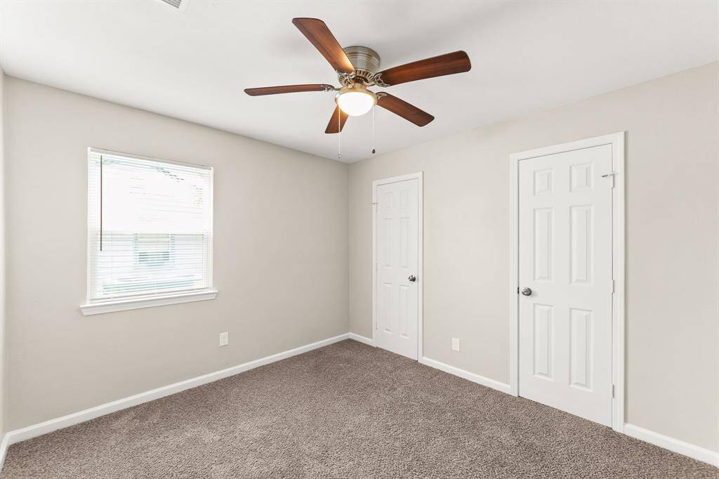 Cozy bedroom with soft carpeting, ample natural light, and a ceiling fan for comfort