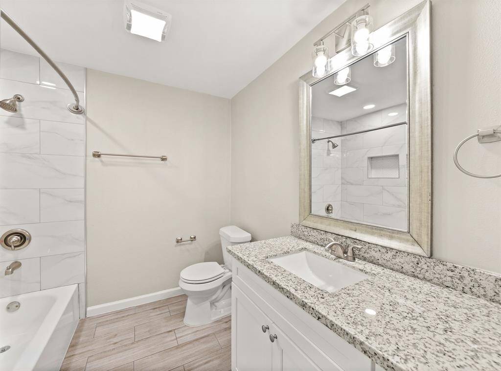 Elegant guest bathroom featuring modern fixtures, sleek granite countertops, and a luxurious tub with stylish tile accents. Perfect for visitors and everyday use