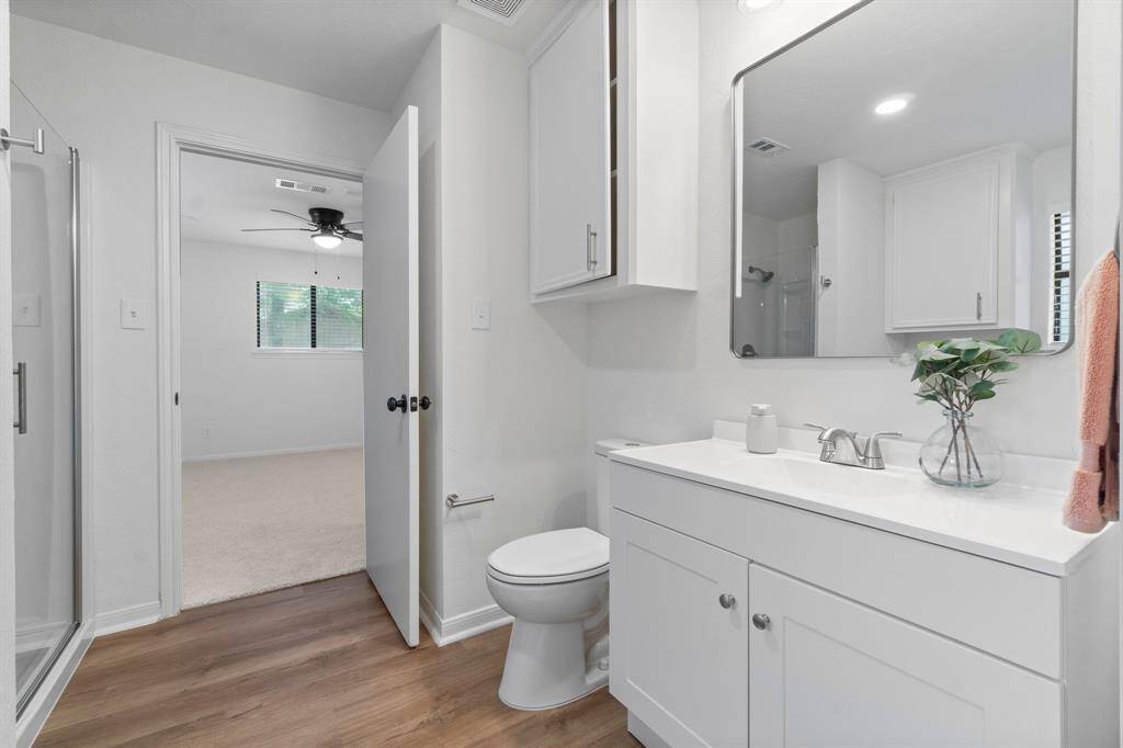 En suite bathroom with stand-alone shower and new vanity. Note the additional cabinet above the new toilet.