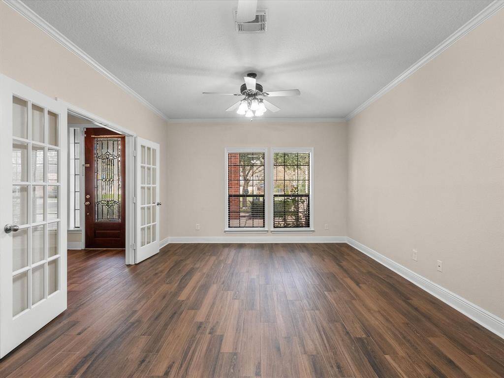 Living /Office area opening to entry with elegant french doors, and dual ceiling fans. Beautiful flooring and crown molding set this room apart.
