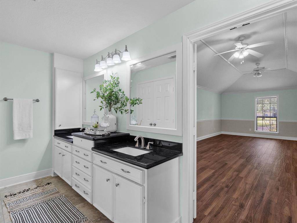 Primary bedroom features en-suite bath with granite counters , dual sinks, lots of storage, and modern decor.