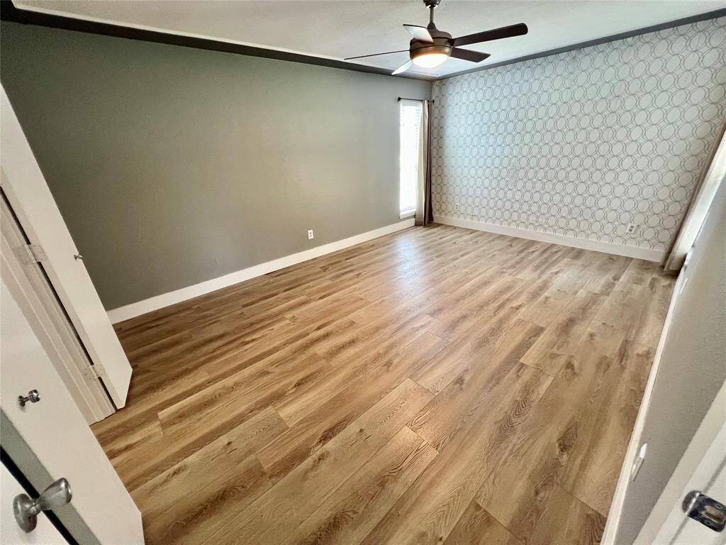 Primary bedroom with plenty space for large furnishings, modern ceiling fan, and geometric accent wall.