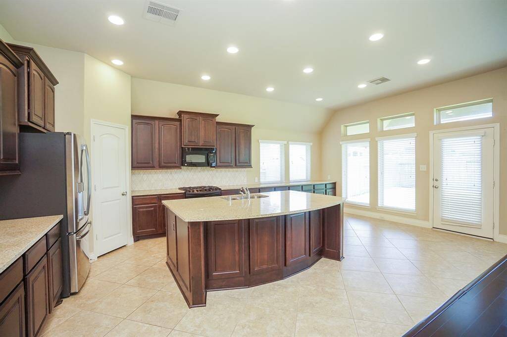 This gorgeous chef's kitchen also contrasts chocolate colored cabinetry with great storage, and granite countertops that seem to go on forever! The area under windows, right, and wide patio door play canvas to a possible breakfast nook.