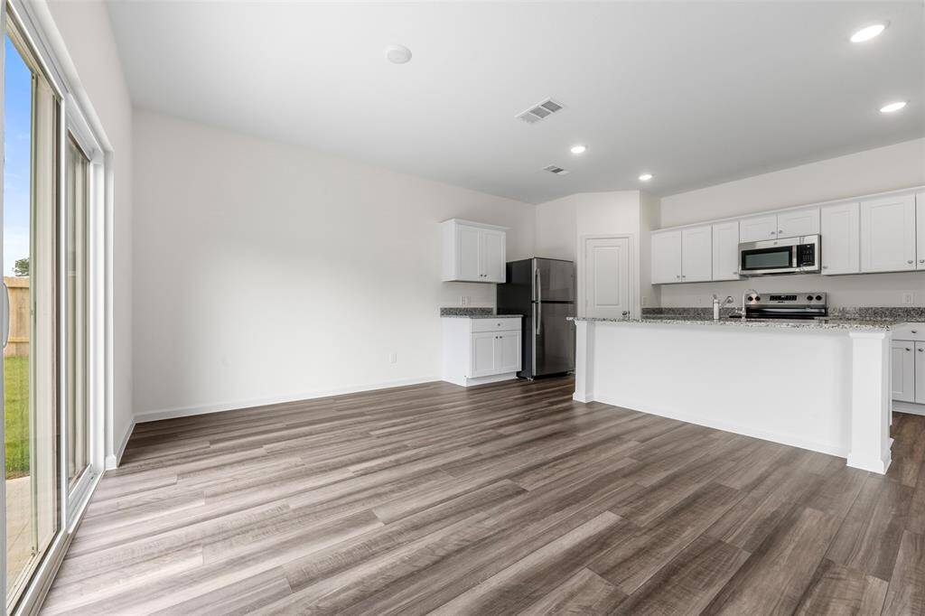 An open-concept living area featuring large windows that flood the space with natural light, neutral-toned walls, and modern flooring, creating a warm and inviting atmosphere.