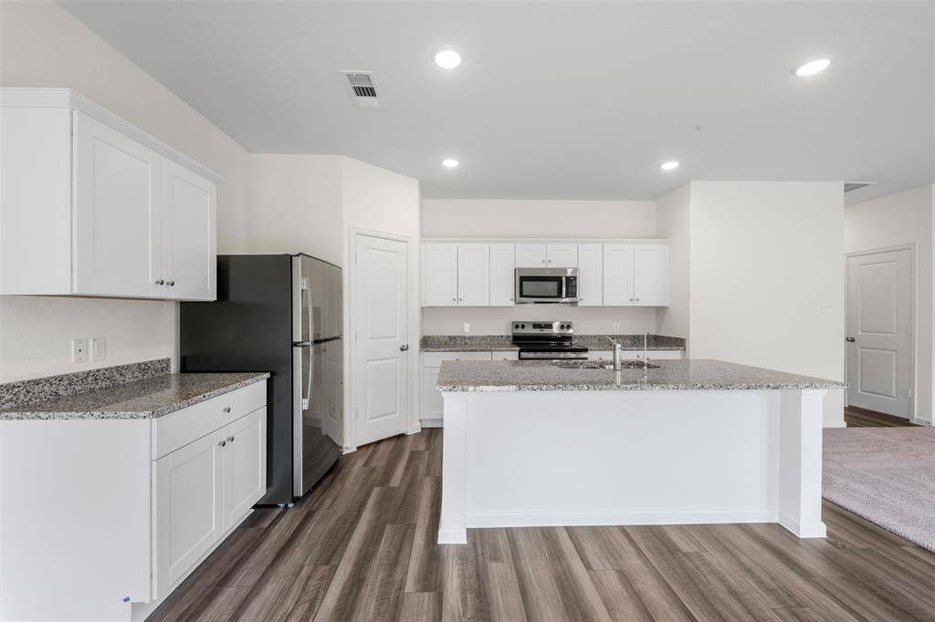A modern kitchen equipped with sleek countertops, stainless steel appliances, ample cabinetry, and a central island, seamlessly connecting to the dining and living areas—ideal for entertaining.