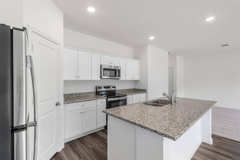 A modern kitchen equipped with sleek countertops, stainless steel appliances, ample cabinetry, and a central island, seamlessly connecting to the dining and living areas—ideal for entertaining.
