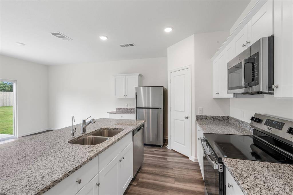 A modern kitchen equipped with sleek countertops, stainless steel appliances, ample cabinetry, and a central island, seamlessly connecting to the dining and living areas—ideal for entertaining.