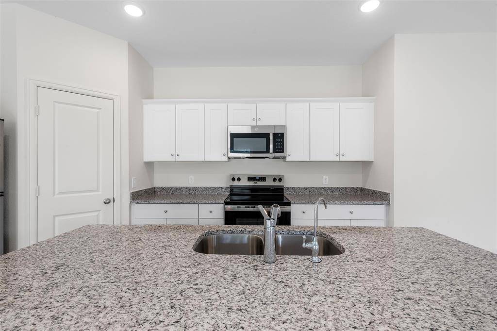 A modern kitchen equipped with sleek countertops, stainless steel appliances, ample cabinetry, and a central island, seamlessly connecting to the dining and living areas—ideal for entertaining.