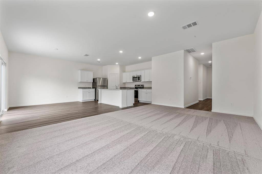 An open-concept living area featuring large windows that flood the space with natural light, neutral-toned walls, and modern flooring, creating a warm and inviting atmosphere.