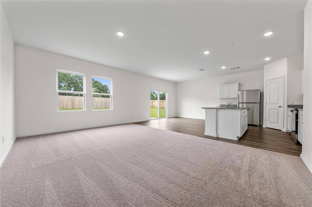 An open-concept living area featuring large windows that flood the space with natural light, neutral-toned walls, and modern flooring, creating a warm and inviting atmosphere.