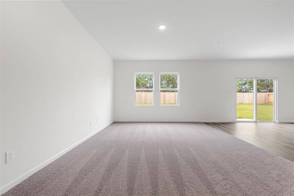 An open-concept living area featuring large windows that flood the space with natural light, neutral-toned walls, and modern flooring, creating a warm and inviting atmosphere.