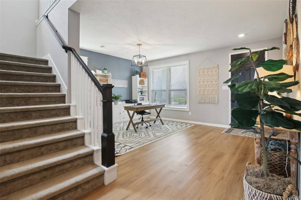 The entrance features elegant wood and iron staircase leading to the second floor. The room is well-lit and offers a warm, inviting atmosphere