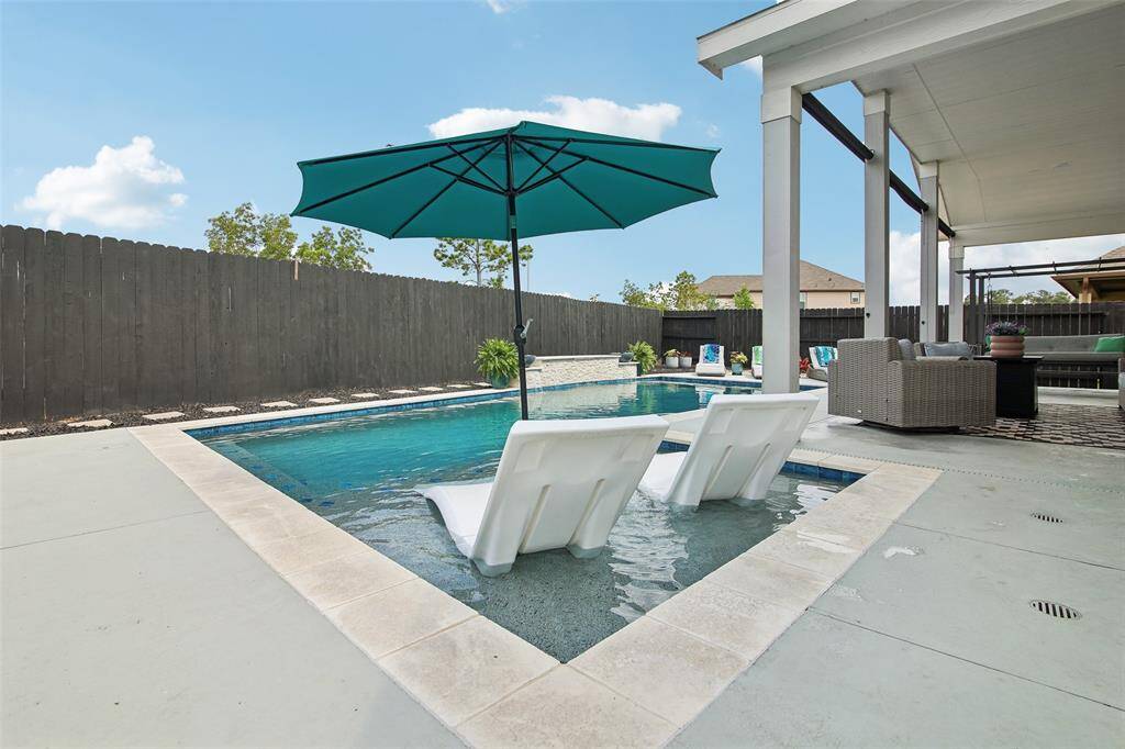 The sparkling pool features a built-in ledge, ideal for soaking up the sun or letting the kids splash safely in the shallow area.