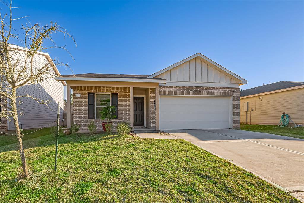 This photo shows a charming single-story brick home with a neatly maintained front yard, a covered porch, and a two-car garage. The driveway is spacious, and the exterior features a combination of brick and siding, giving it a modern yet cozy appearance.