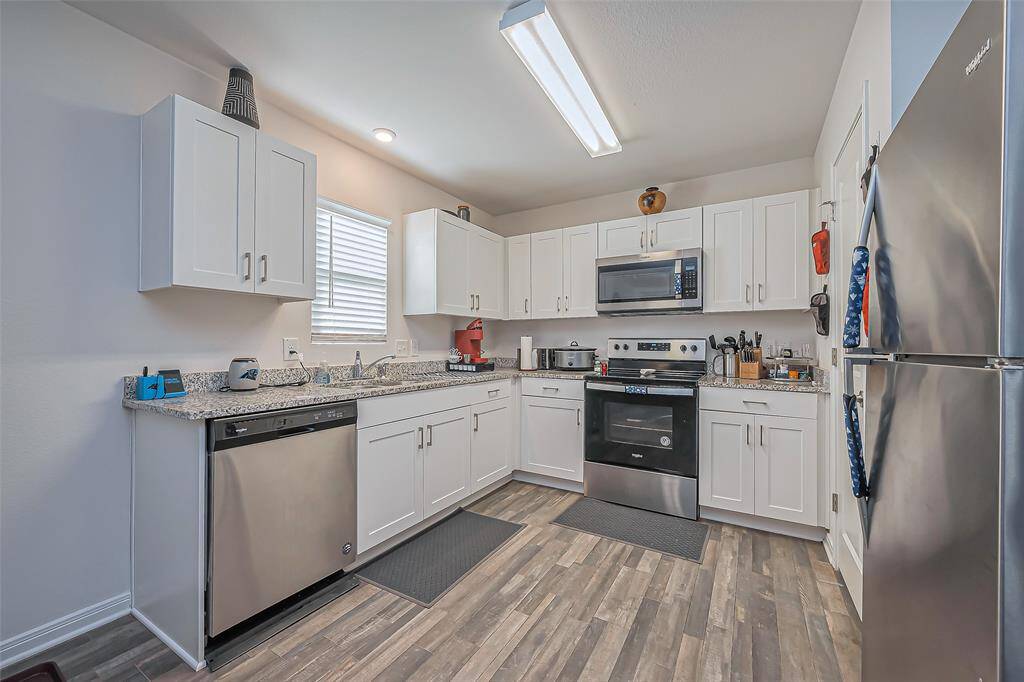 This kitchen features sleek stainless steel appliances, white cabinetry, and granite countertops. The space is well-lit with a modern overhead light and has a practical layout ideal for cooking and entertaining.