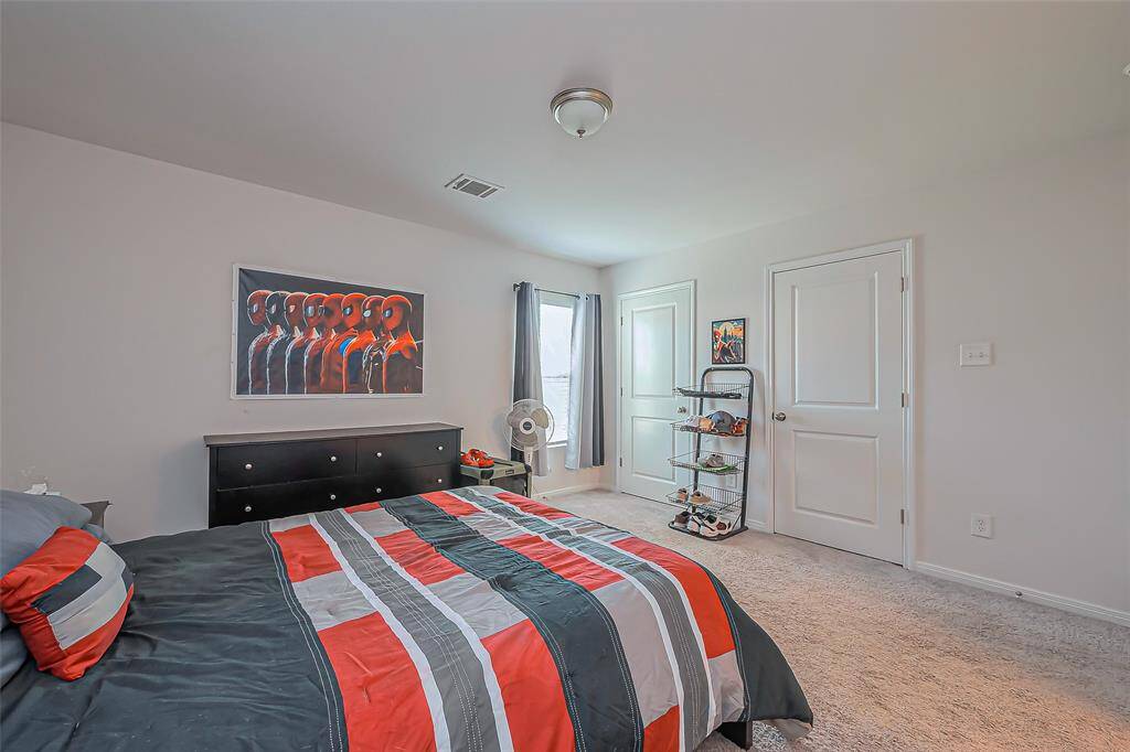 This bright bedroom features neutral walls, cozy carpeting, and ample natural light. It includes a double-door closet, modern light fixture, and space for a dresser and shelving. Perfect for a comfortable, personalized retreat.