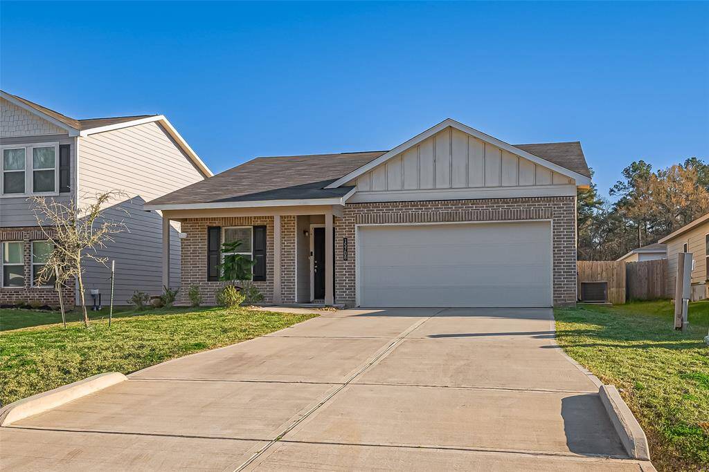 This is a charming single-story home featuring a brick exterior and a welcoming front porch. It has a two-car garage and a spacious driveway. The yard is well-maintained with a small tree and plants, providing a pleasant curb appeal.