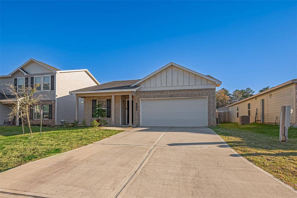 This photo features a modern single-story home with a brick and siding exterior. It has a two-car garage, a well-maintained driveway, and a small front porch. The surrounding lawn is neatly trimmed, and the neighborhood has similar styled houses.