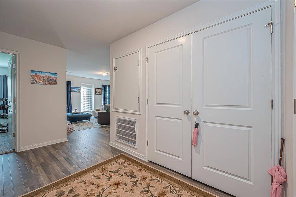 This photo showcases a welcoming entryway with a double-door closet and hardwood flooring. It opens up to a bright living area with large windows and ample natural light. Suitable for a cozy and functional home environment.