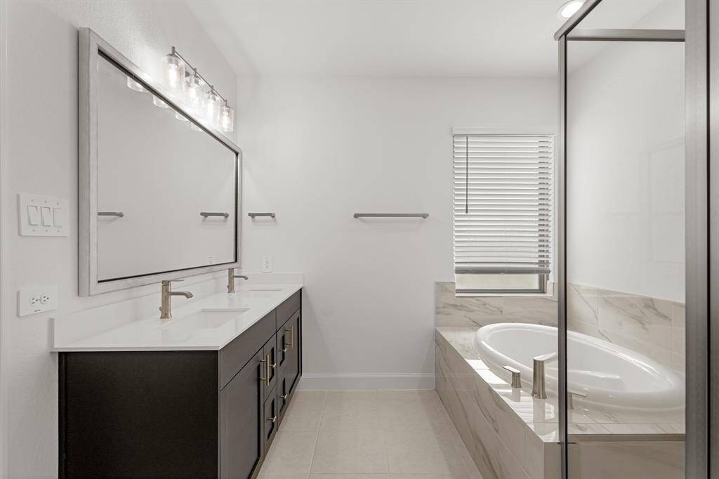 Welcome to your very own retreat! Relax after a long day in this wonderful Primary Bathroom with beautiful wood cabinetry, double sinks, and modern fixtures.