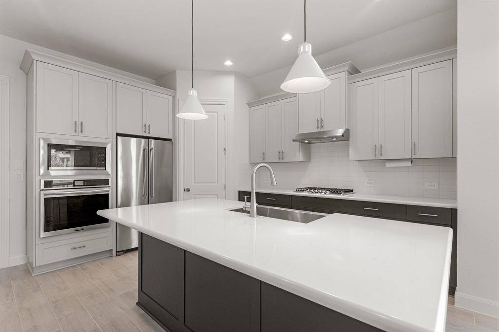 The kitchen is fully equipped with stainless steel appliances, a walk-in pantry, recessed lighting, and custom J Kraft cabinetry.