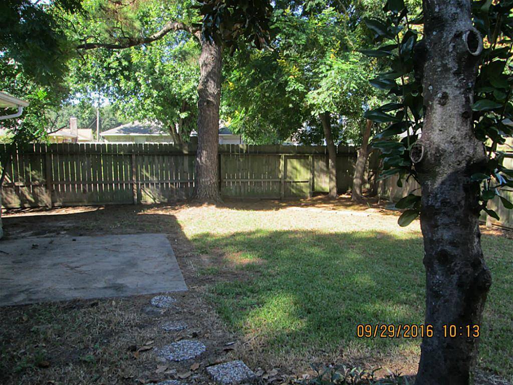 Large concrete patio in back yard with plenty of shade trees and a magnolia.