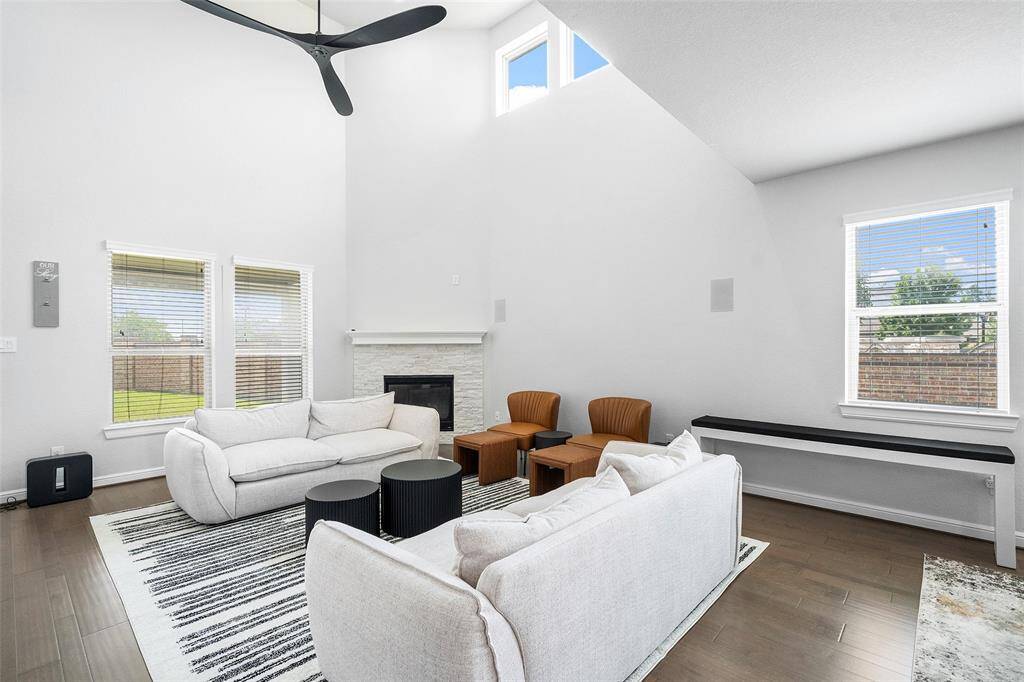 Soaring ceilings and a stunning fireplace anchor the gorgeous open living room, creating a warm and inviting space perfect for relaxing or entertaining.