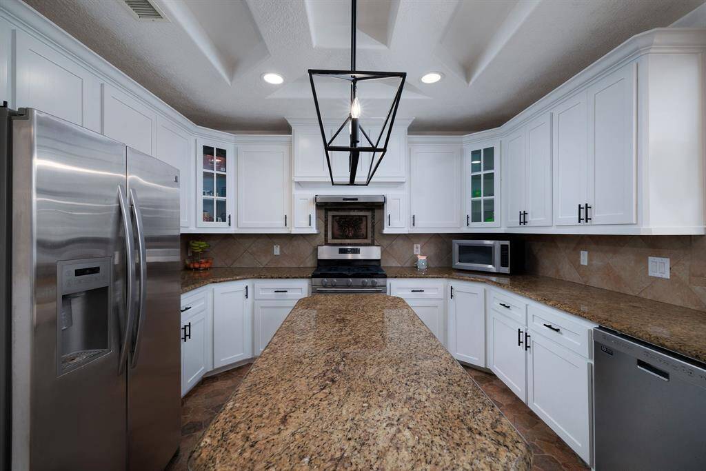 This beautiful island kitchen features granite countertops, refaced cabinets, fresh paint, and stainless steel appliances.