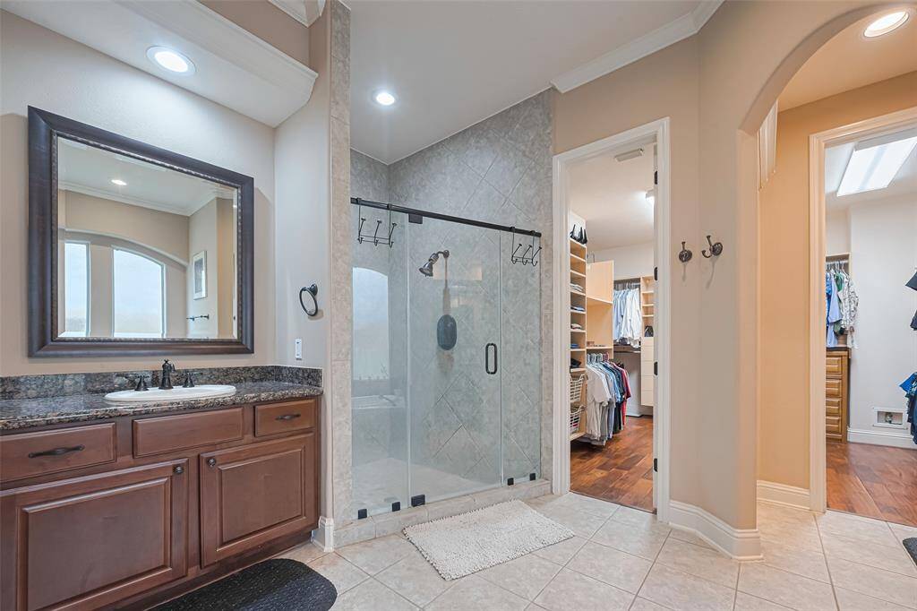 Luxury continues with a frameless walk-in shower, elegant tilework, and seamless access to a large walk-in closet for everyday convenience