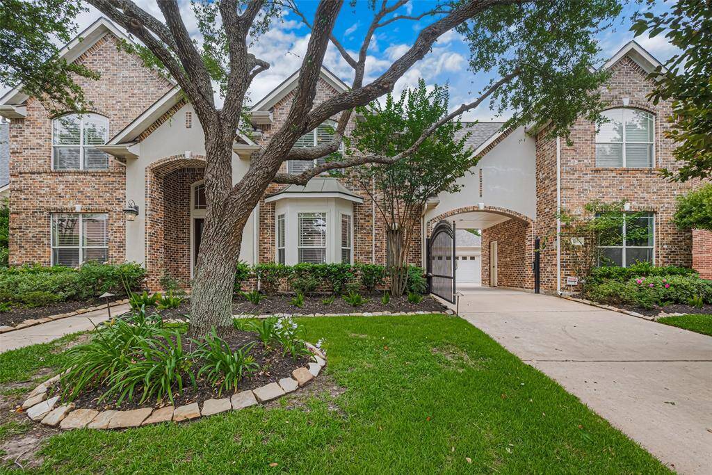 The elegant arched entryway with double front doors, flanked by decorative sconces, sets a grand tone
