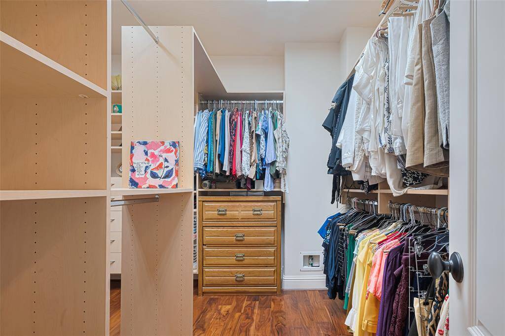Spacious custom walk-in closet with built-in shelving, dual hanging sections, and wood-style flooring—designed for optimal organization and storage
