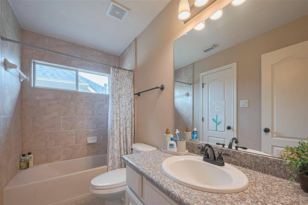 This full bath features a granite vanity countertop, a sleek undermount sink, and classic tile finishes that extend into the shower/tub combo