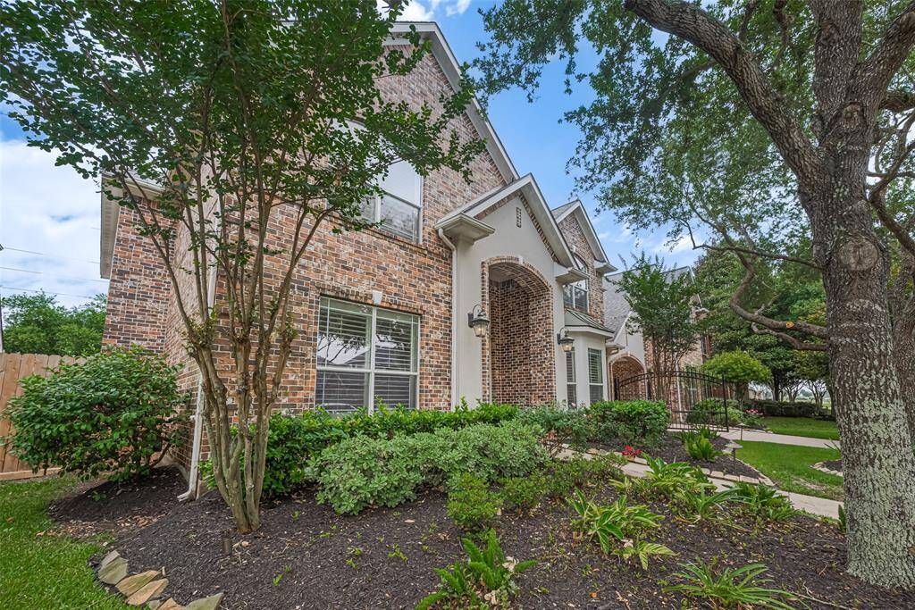 Manicured landscaping with lush greenery, blooming flower beds, and a mature shade tree enhances the home's inviting charm